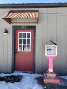 photo of a modern sharing library painted bright pink outside an office door